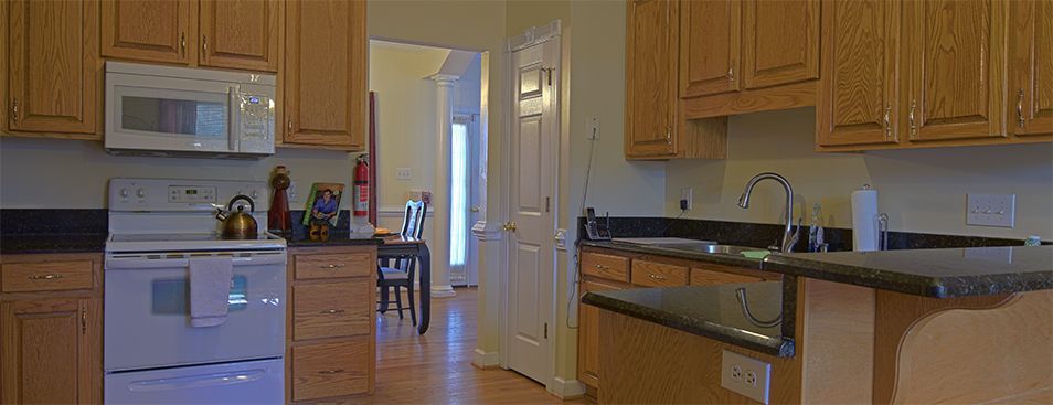 A view of a kitchen with wooden cabinets and a doorway leading to a dining area.