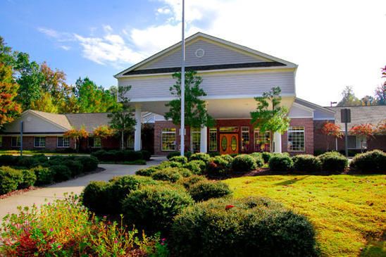 A well-maintained building surrounded by lush landscaping and greenery on a sunny day.