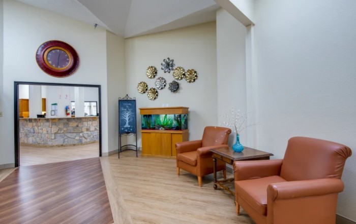 A cozy waiting area with comfortable chairs, wall art, and an aquarium.