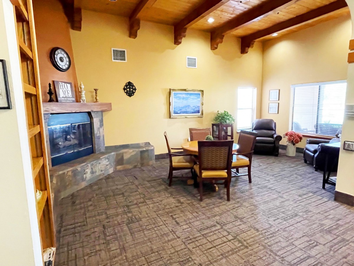Cozy living room with a fireplace and wooden ceiling beams, featuring a dining table and comfortable seating.