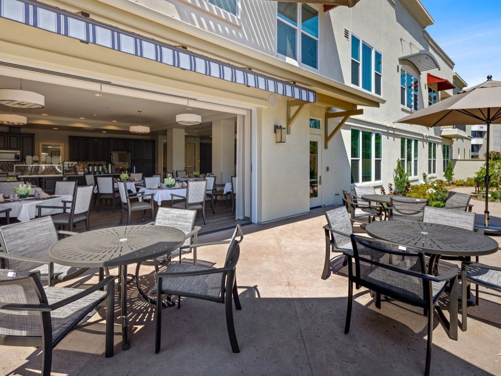 Outdoor seating area at a restaurant with tables and chairs on a sunny day.