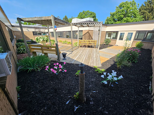 A serene garden space featuring colorful flowers and a wooden pergola under a clear blue sky.