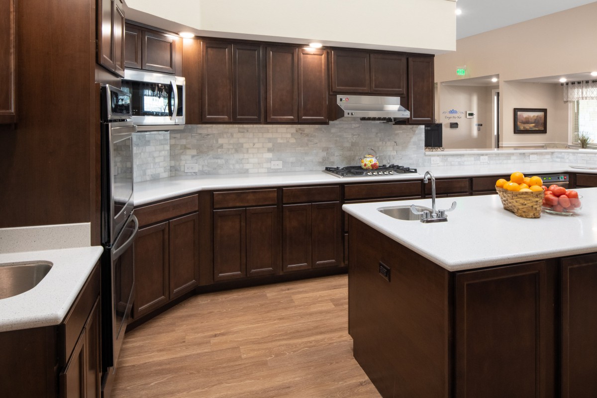A modern kitchen with dark wood cabinets, a central island, and built-in appliances.