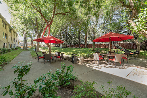 A peaceful outdoor garden area equipped with tables and red umbrellas, perfect for relaxation and gatherings.