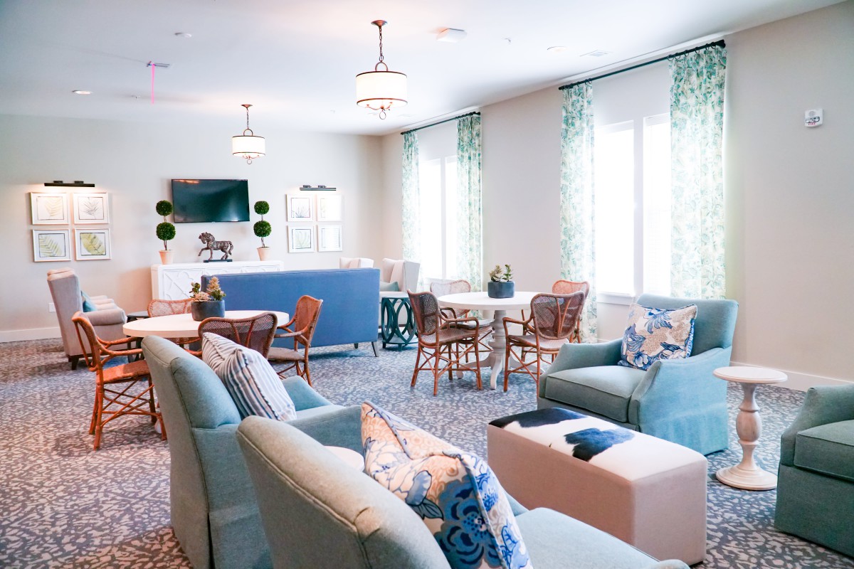 A well-lit living room featuring comfortable sofas, a coffee table, chairs, and a TV.