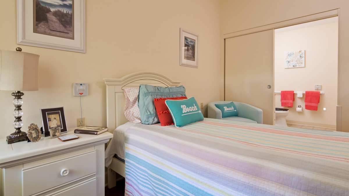 A cozy bedroom with a neatly made bed, colorful pillows, and simple decor.
