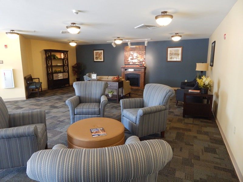 A cozy living room with striped armchairs, a round wooden table, and a bookshelf in the background.