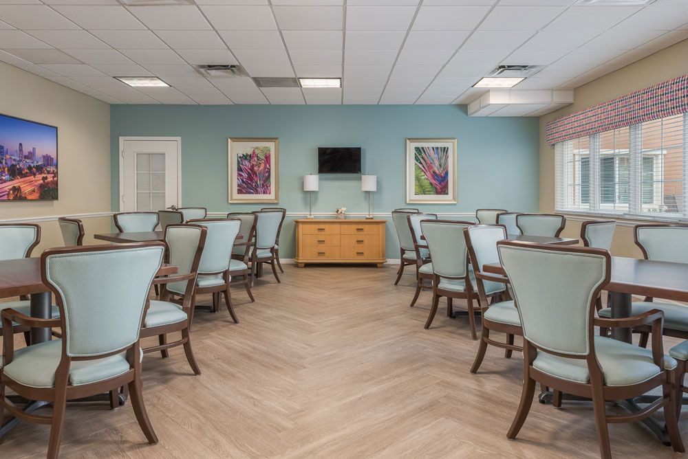 A modern dining room with neatly arranged tables and chairs, featuring art on the walls and a television.