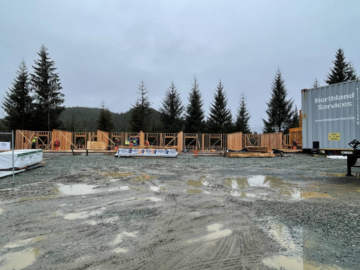 A construction site with wooden frames surrounded by trees on an overcast day.