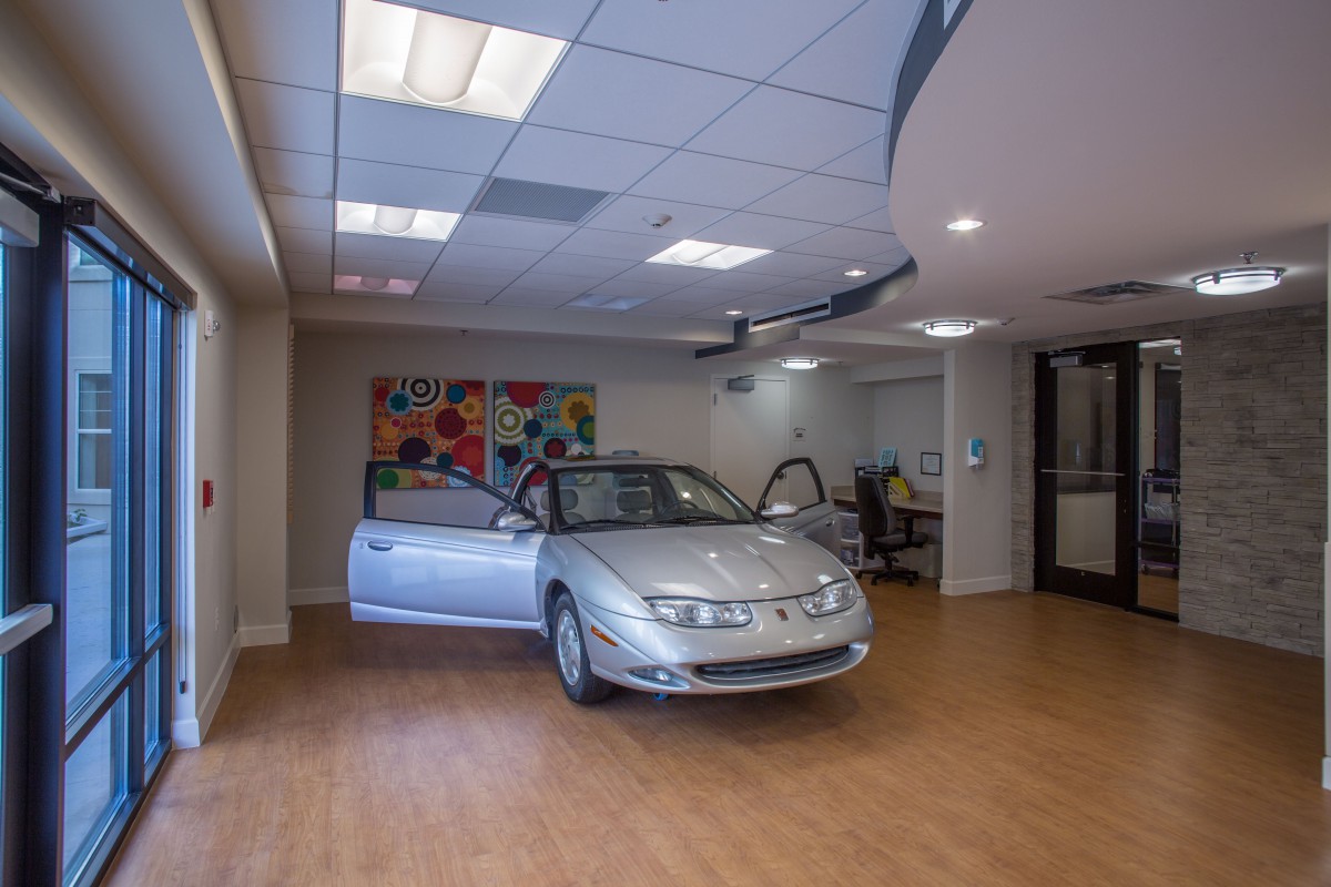 A car on display inside an indoor showroom with art on the wall.