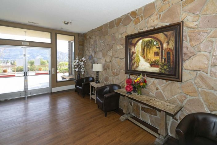 A warmly decorated entryway featuring a stone wall with a large painting, wood flooring, and stylish furniture.