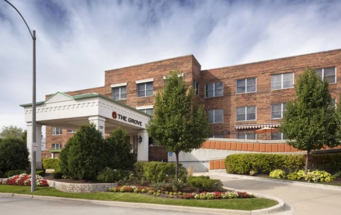 A brick healthcare building with a main entrance and surrounding greenery.