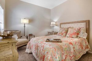 A cozy bedroom with a patterned bedspread, bedside tables, and warm lighting.