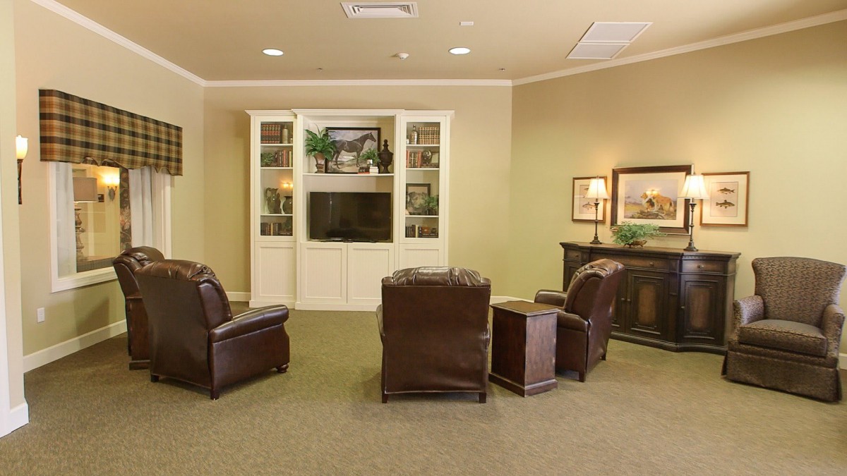 A cozy living room with leather chairs and a television set in front of built-in bookshelves.