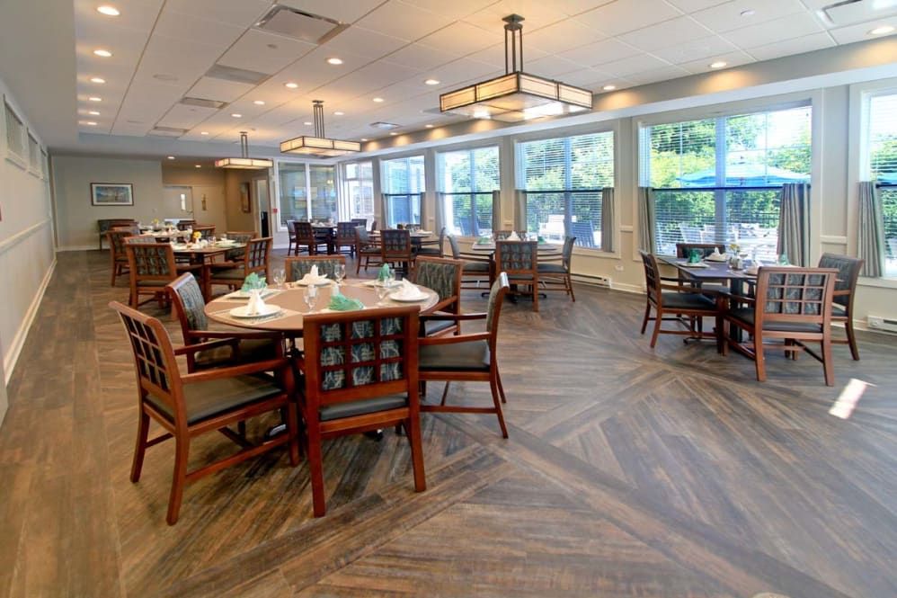 A spacious and well-lit dining area with neatly arranged tables and chairs, featuring large windows and stylish lighting.