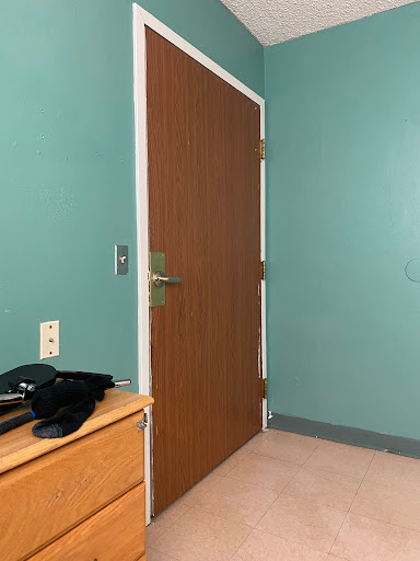 A view of a room featuring a wooden door and teal-colored walls.