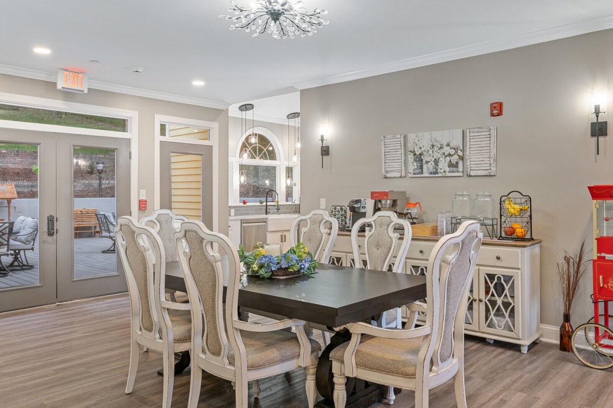 An elegant dining room with a dark wooden table surrounded by ornate chairs, adorned with tasteful decor and a modern chandelier.
