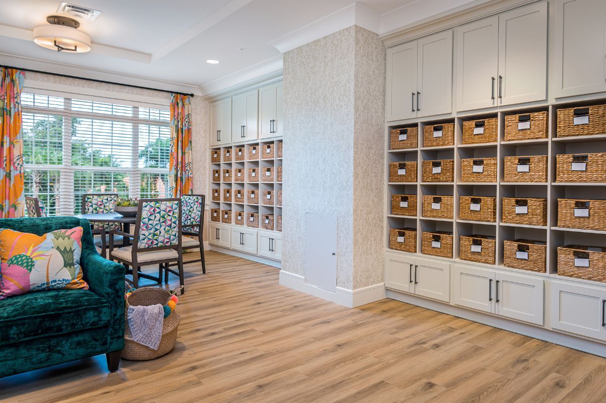 A well-organized room with wooden flooring, featuring shelving units filled with boxes and a window providing natural light.