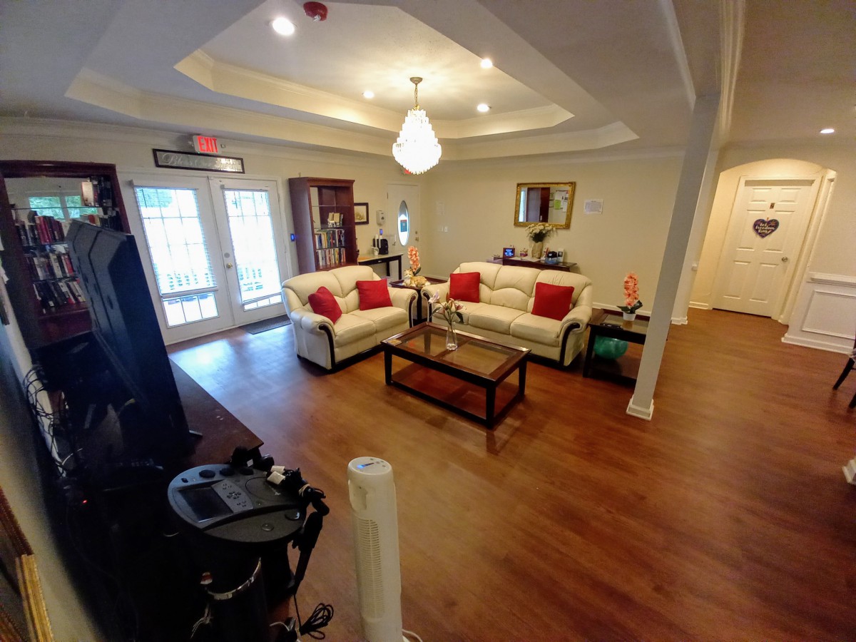 A cozy living room featuring white sofas with red cushions, a wooden coffee table, and wood flooring.
