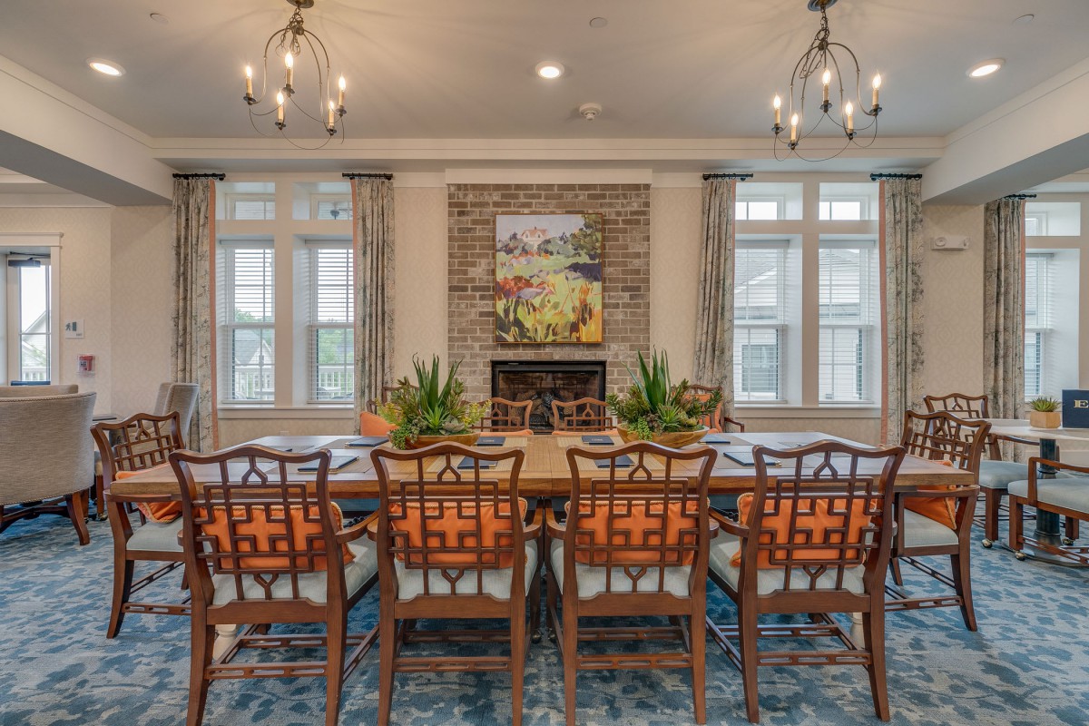 Elegant dining room with a large table and chandeliers, featuring a fireplace and artwork.