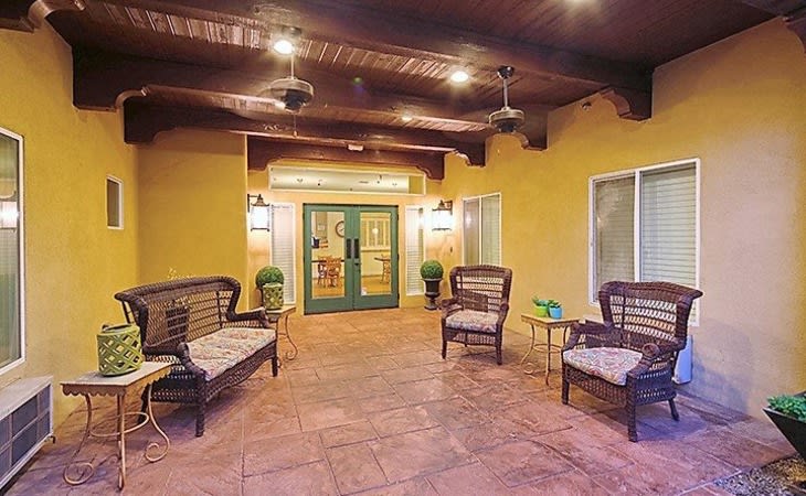A cozy outdoor patio with wicker seating and ceiling fans.