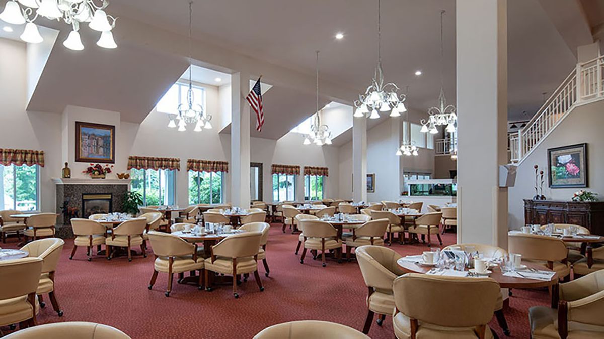 An elegantly designed dining area featuring multiple tables and plush seating, illuminated by chandeliers.