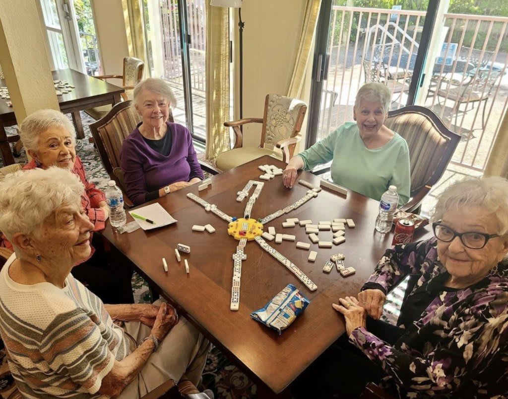 A group of senior women enjoying a game of dominoes indoors.
