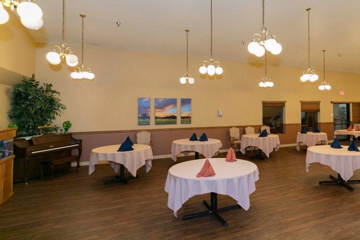 An elegant dining room with round tables, neatly arranged table settings, and soft lighting.