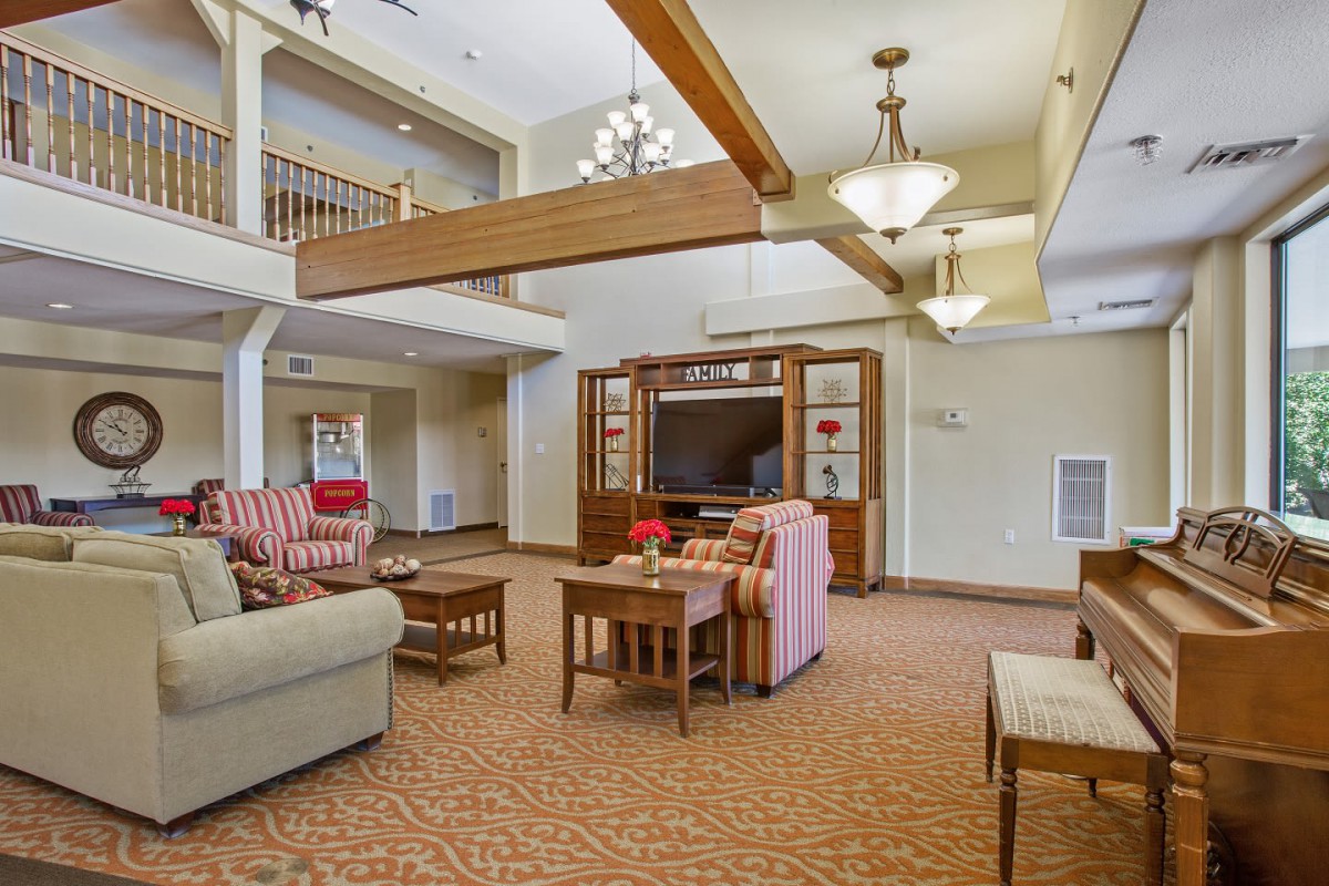 A cozy living room with sofas, wooden beams, and chandeliers.