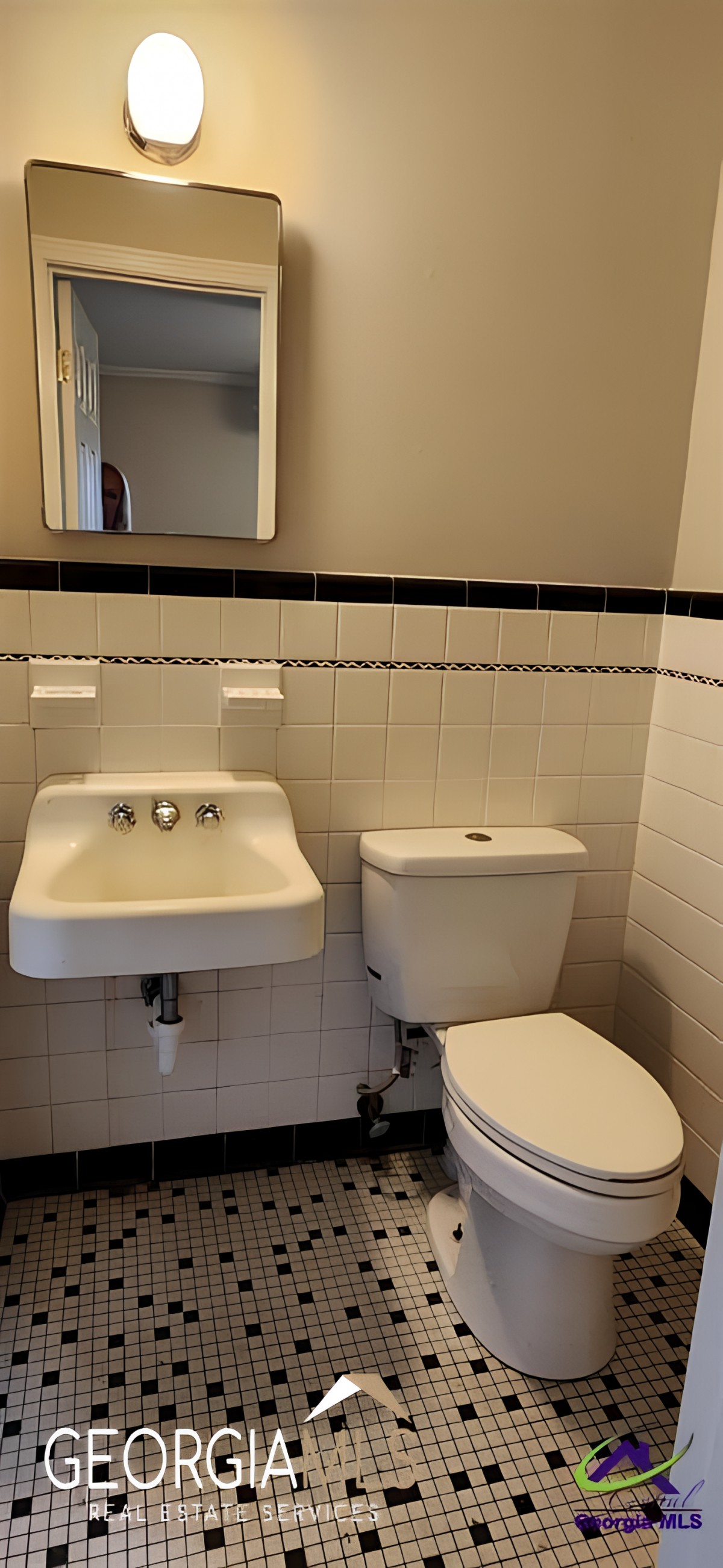Small bathroom interior with a sink, toilet, and wall-mounted mirror.