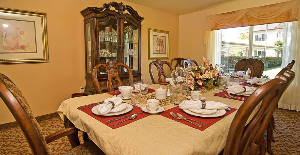 A dining room with a table set for a meal, complete with plates, cups, and a floral centerpiece.