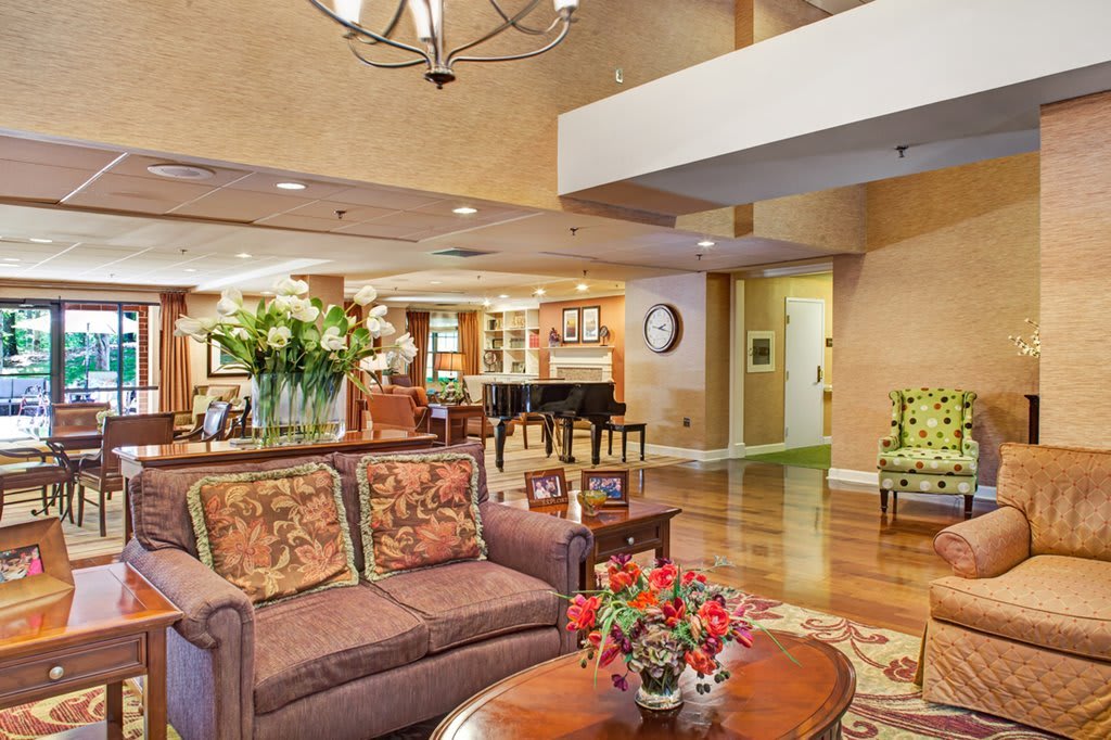 A beautifully decorated living room featuring a cozy sofa, elegant coffee table with flowers, and a grand piano.