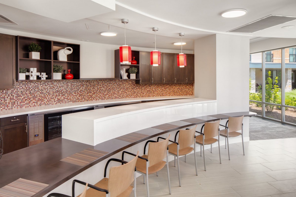 A modern kitchen interior with a curved counter and stylish chairs, featuring contemporary lighting and decor.