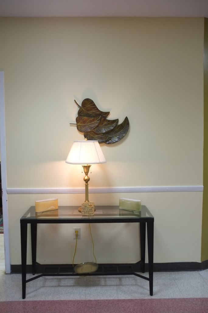 A cozy interior setup featuring a table lamp and decorative wall art above a glass-topped table.