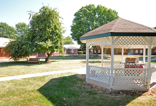 A peaceful park setting featuring a gazebo surrounded by trees and grassy areas.