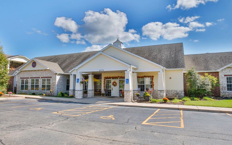 A building with a welcoming entrance and a spacious parking lot under a cloudy sky.