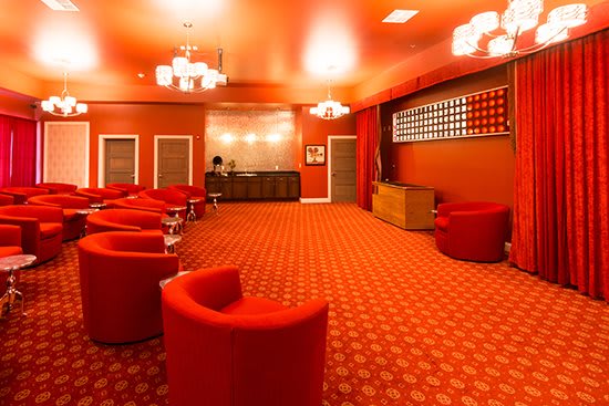 A stylish red lounge featuring modern seating and elegant chandeliers.
