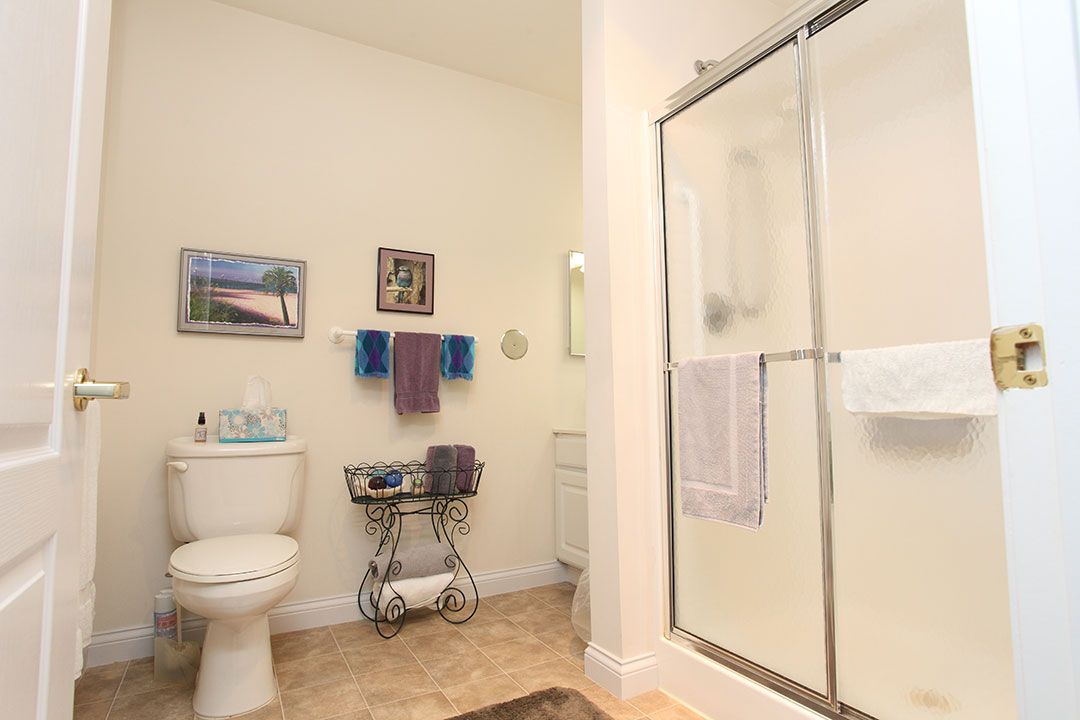 A modern bathroom with a glass shower, toilet, and neatly arranged towels.