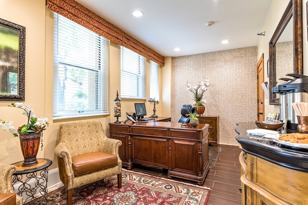 A well-decorated office space with a wooden desk, upholstered chairs, and a patterned carpet.