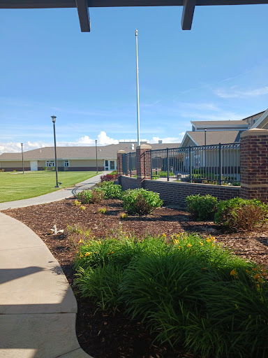 A well-maintained outdoor area featuring a pathway, garden beds, and buildings under a clear blue sky.