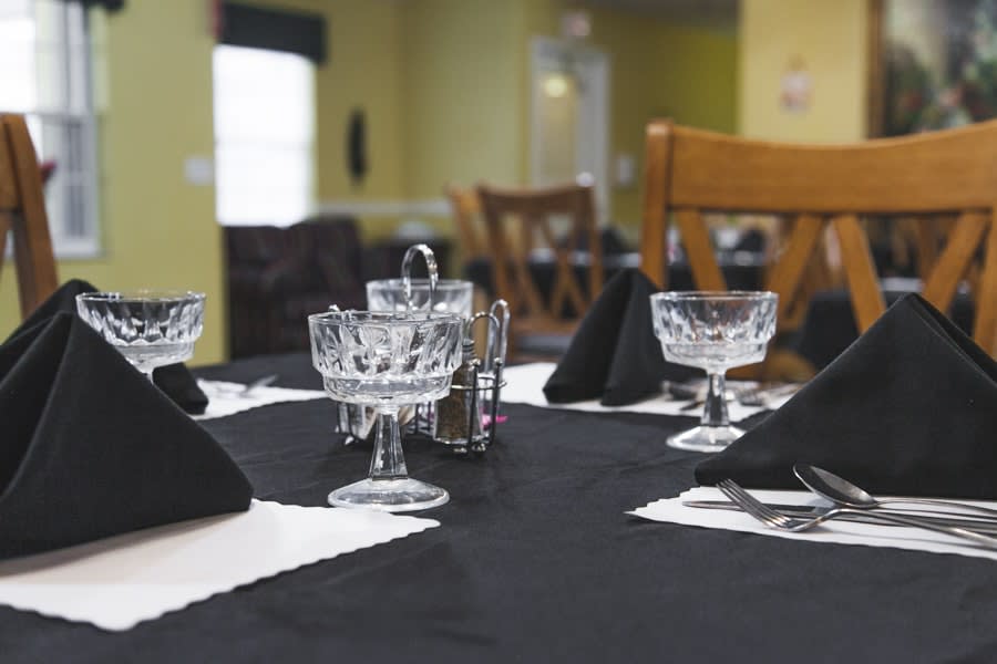 A dining table set in a restaurant with crystal glasses and black napkins.