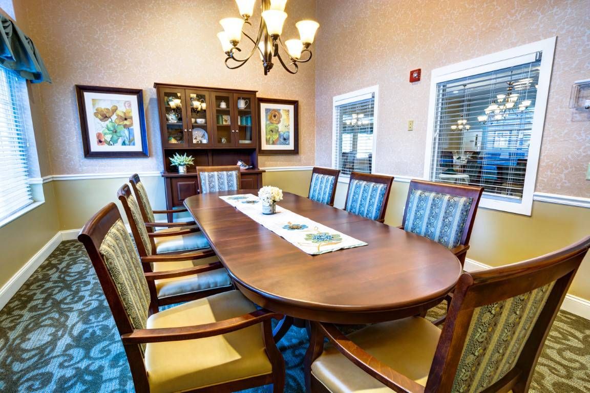 A well-decorated dining room with a wooden table, elegant chairs, a chandelier, and artwork on the walls.
