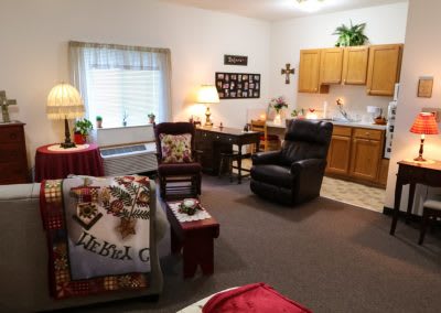 A cozy living area with a kitchenette, featuring comfortable furniture and warm decor.