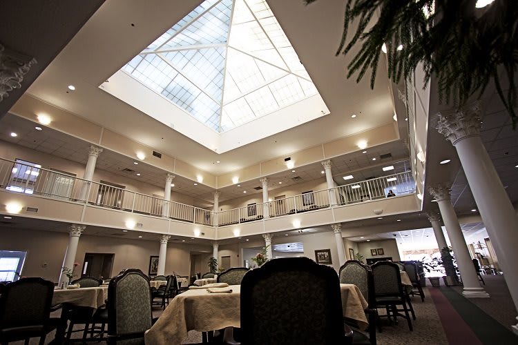 An interior view of a spacious dining area with a skylight atrium, surrounded by tables and chairs.