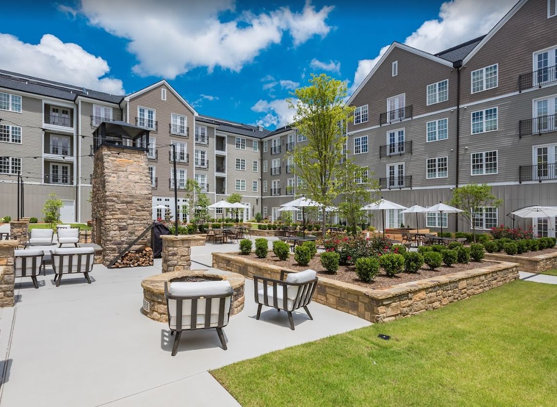 A well-maintained apartment courtyard featuring a spacious seating area and elegant landscaping on a sunny day.