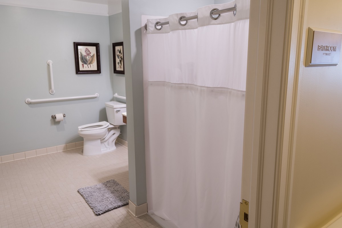 A clean bathroom with a shower, toilet, and decorative wall art.