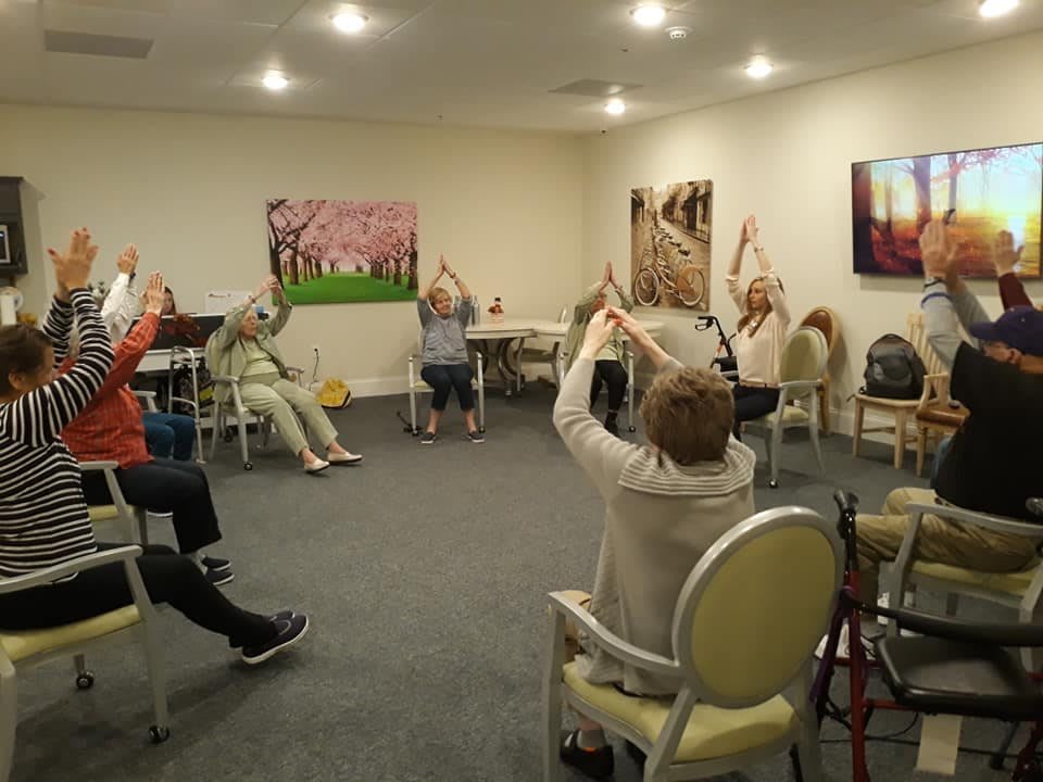 A group of seniors participating in a seated exercise class at a community center.