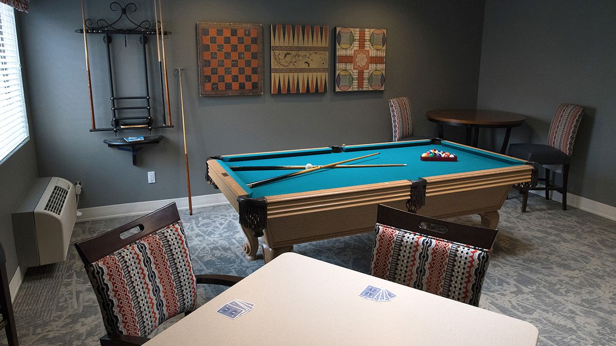 A cozy game room featuring a pool table, chairs, and wall art.