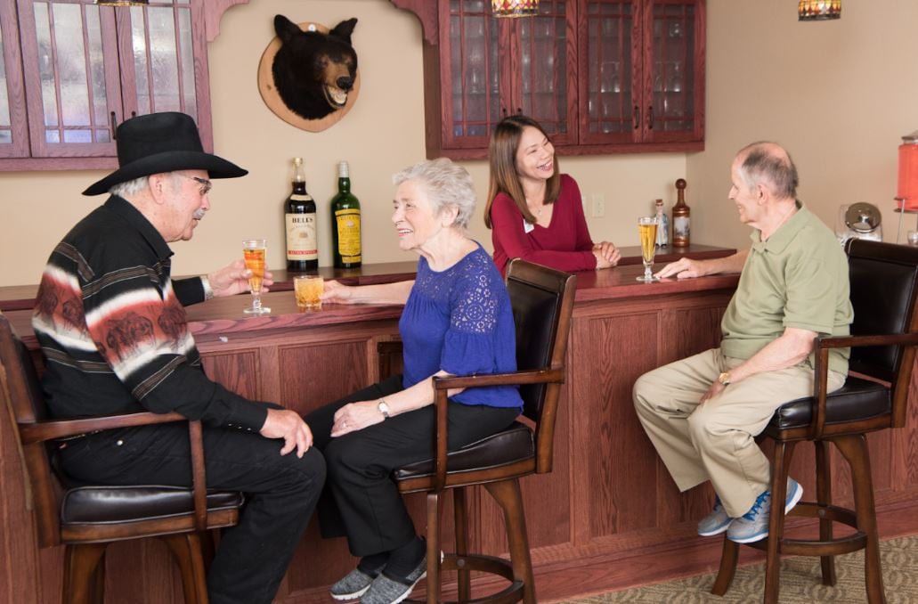 A group of people socializing at a home bar with drinks.