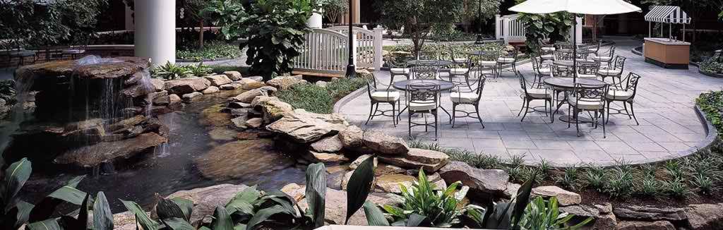 A tranquil garden patio with outdoor seating and a rock-lined water feature.